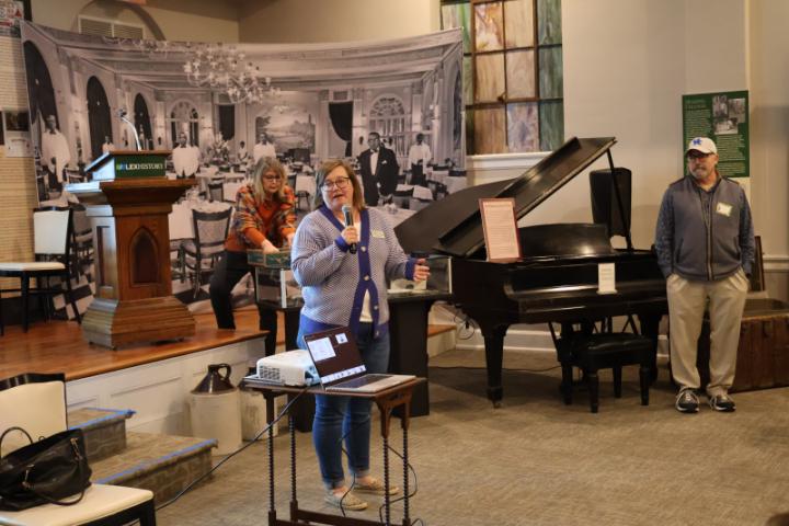A picture of Dr. Amanda Higgins, director at the Thomas Hunt Morgan House, giving an introduction with Jacquie Burke and Dr. Pete Mirabito in the background.