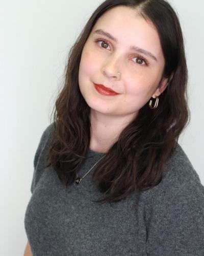 A woman with dark hair and a gray shirt looks at the camera.