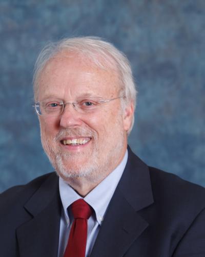 A man wearing a suit and smiling at the camera.