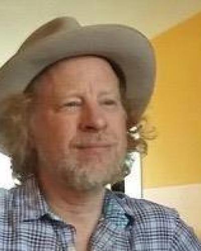 A man wearing a cowboy hat and a blue plaid shirt.