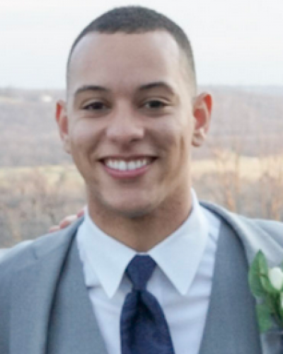 A smiling man in a gray suit with a white shirt and blue tie.